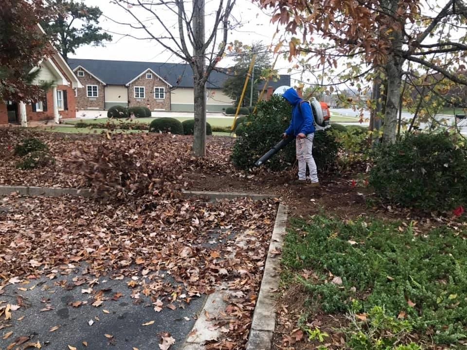 Crew member blowing leaves off a lawn and walkway